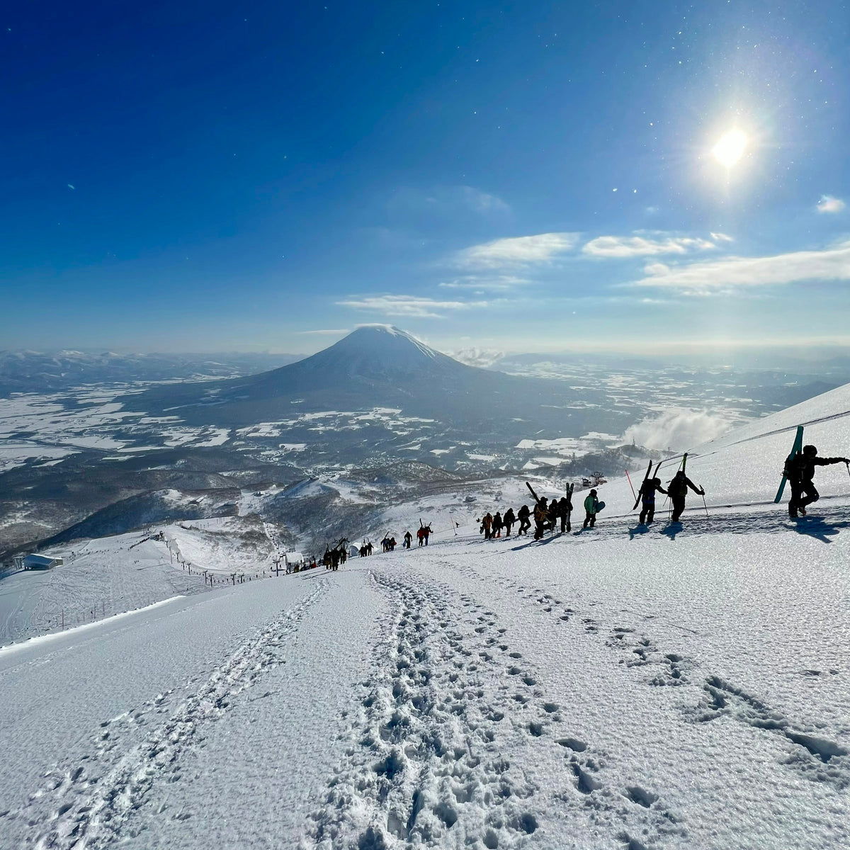 二世谷山脊上徒步前往粉雪路線的滑雪者，遠處為羊蹄山